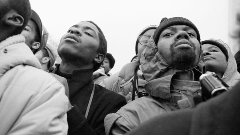 a black and white, close-up photograph of two men standing. 